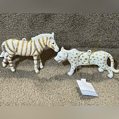 two zebra figurines sitting on the ground next to each other