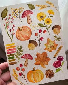 a person holding up a card with autumn leaves and mushrooms on it