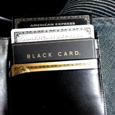 an american express black card sitting on someone's jeans