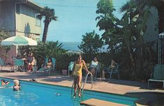 a woman in a yellow bathing suit standing next to a swimming pool with palm trees