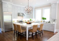 a large kitchen with white cabinets and wooden flooring, along with a dining table surrounded by chairs