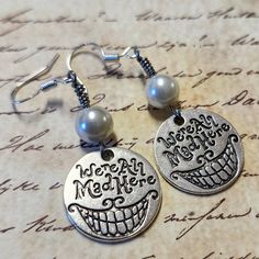 two silver earrings with words on them