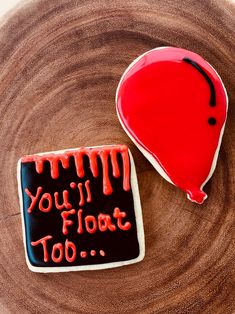 two decorated cookies sitting on top of a wooden plate with the words you'll float too