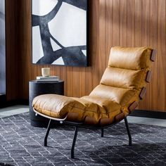 a brown recliner chair sitting on top of a rug in front of a painting