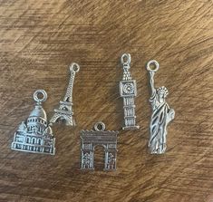 three charms sitting on top of a wooden table next to a clock tower and statue of liberty