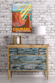 a wooden dresser sitting next to a brick wall with a poster on it that says colorado national monument