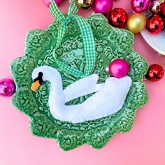 an ornament shaped like a swan on a green plate with ornaments around it