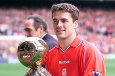 a man holding a soccer ball and trophy