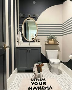 a bathroom with black and white stripes on the walls, a rug that says wash your hands