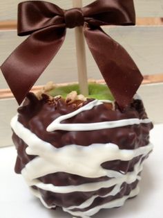 a chocolate covered apple with white icing and a brown bow