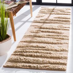 a white rug on the floor next to a chair and potted plant in front of a window