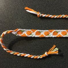 two orange and white bracelets sitting on top of a black table next to each other