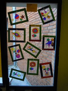 some pictures are hanging on the wall behind a glass door that has been decorated with different colors and shapes