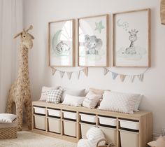 a nursery room with three pictures on the wall and two stuffed animals hanging above it