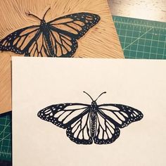 a butterfly is sitting on top of a piece of paper next to a cutting board