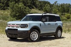 a blue and white suv parked on top of a dirt road