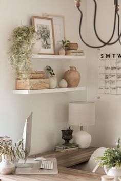 a desk with a lamp and pictures on the wall above it, along with other items