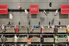 many pairs of gloves are hanging on the wall next to bins filled with clothes