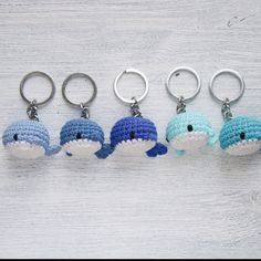 four crocheted keychains with dolphins on them sitting in front of a white wooden background