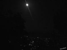 the moon is shining in the night sky over some trees and buildings with lights on them