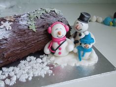 two snowmen are standing next to a log on a table with white frosting