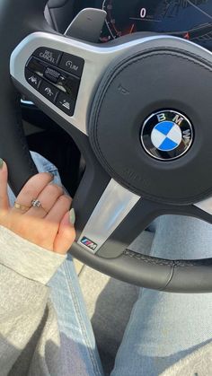 a woman is holding the steering wheel of a car while she's sitting down