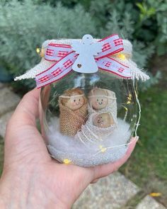 a hand holding a glass ornament with two teddy bears in it