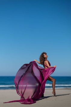 a woman in a purple dress on the beach