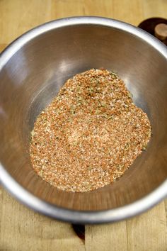 a metal bowl filled with spices on top of a wooden table