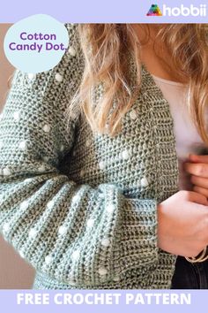 a woman is holding her cell phone while wearing a green cardigan with white polka dots