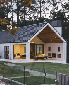 a white house with an open porch and covered patio in the evening light, surrounded by trees