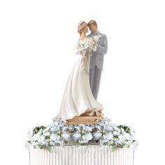 a figurine of a bride and groom on top of a cake with flowers