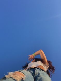 a woman flying a kite high in the sky with her hands on her hips and arms outstretched