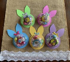 four plastic easter decorations on a table with lace doily and burlap placemat