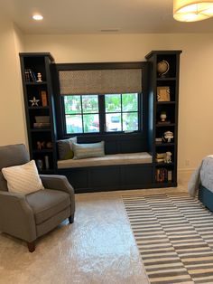 a bedroom with a bed, chair and bookcases in front of a window