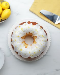 a frosted donut sitting on top of a white plate next to lemons