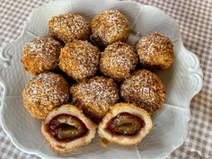 a white bowl filled with pastries covered in powdered sugar on top of a checkered table cloth