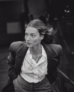 a black and white photo of a woman with her hair in the air, wearing a jacket