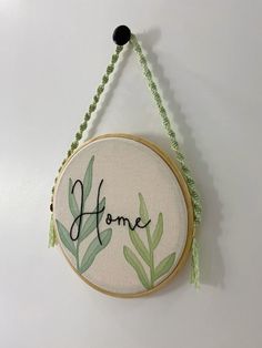 a hand embroidered home sign hanging on a wall