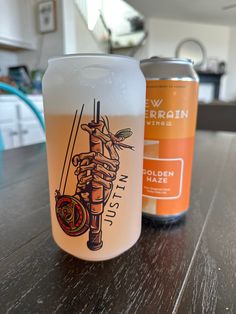 two beer cans sitting on top of a wooden table