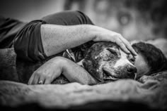 a man laying on top of a bed next to a dog