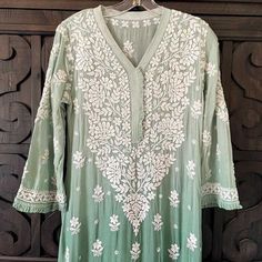 This Ombre Green Lucknowi Chikankari Muslin Kaj Patti Frill Kurti is a staple for any wardrobe. Crafted from Muslin Silk, this piece offers a stylish, elegant look with a frill design detail on the neck and sleeves. A-Line Muslin silk Length 45" inches Long sleeves 18" inches V neck Chikankari embroidery Hand embroidered Dry Clean Fit: True to sizeInside Margin: NoTouch and Feel: Soft and ComfortableDispatched in 1-3 business days Disclaimer: Since the product is hand embroidered, Motifs may var Phulkari Pants, Lehenga Green, Lucknowi Kurta, Chikankari Lehenga, Ombre Green, Chikankari Embroidery, Trendy Outfits Indian, Lucknowi Chikankari, Embroidered Motifs