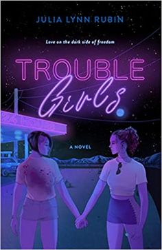 two women holding hands in front of a neon sign that says trouble girls on it