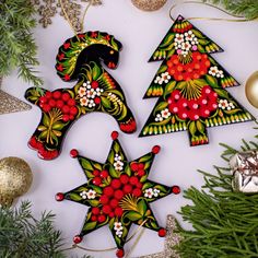 three decorated christmas tree ornaments sitting on top of a table