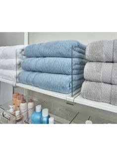 towels are stacked on top of each other in a bathroom shelf next to bottles and soaps