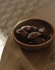 a wooden bowl filled with raisins on top of a table