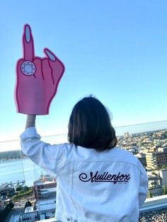 a woman holding up a pink peace sign on top of a building