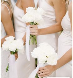 the bridesmaids are holding their bouquets with white flowers in each one's hands