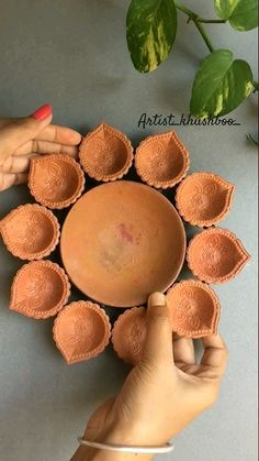 a person holding a clay bowl in front of a plant and another hand reaching for it