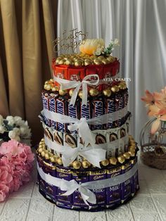 a multi layer cake made out of chocolates and candy bar wrappers with flowers on top